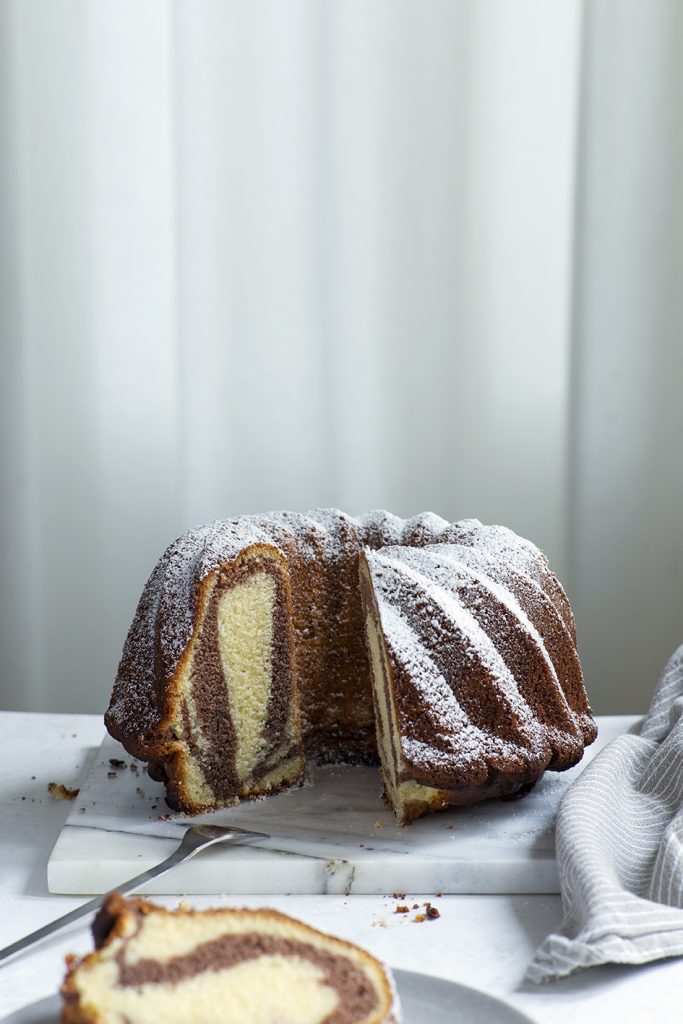 Angeschnittener Marmorkuchen in Gugelhupfform mit Puderzucker