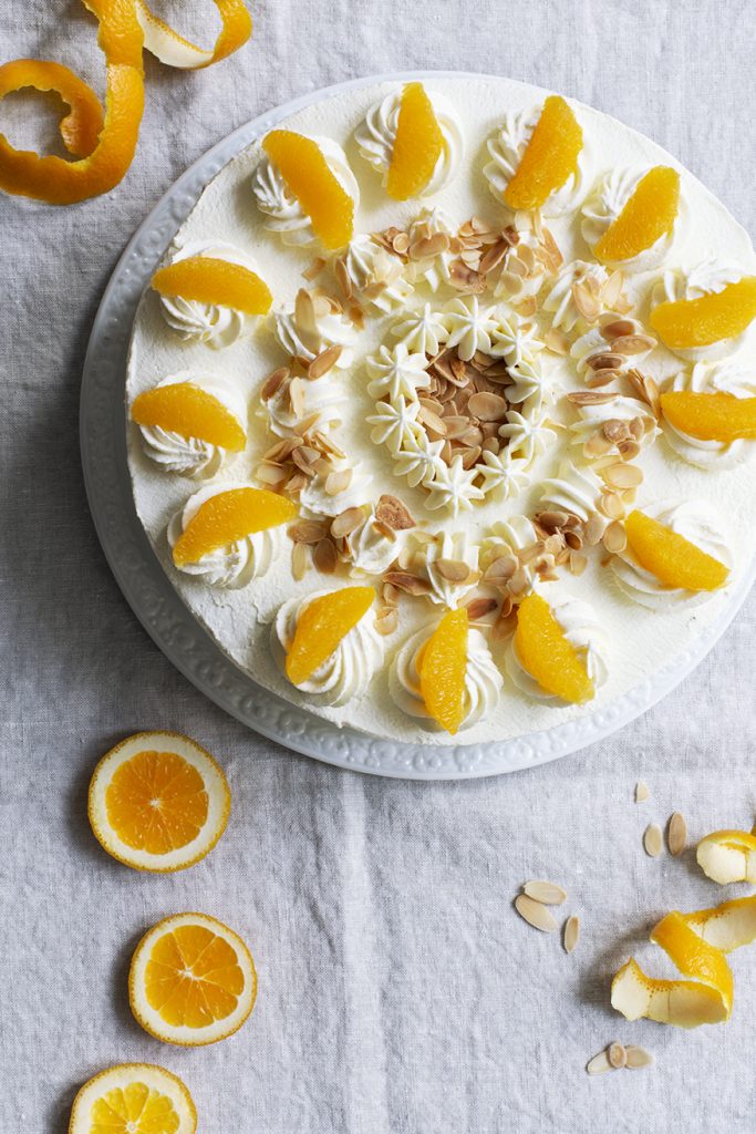 Sahnetorte verziert mit Orangenfilets und Mandelsplittern